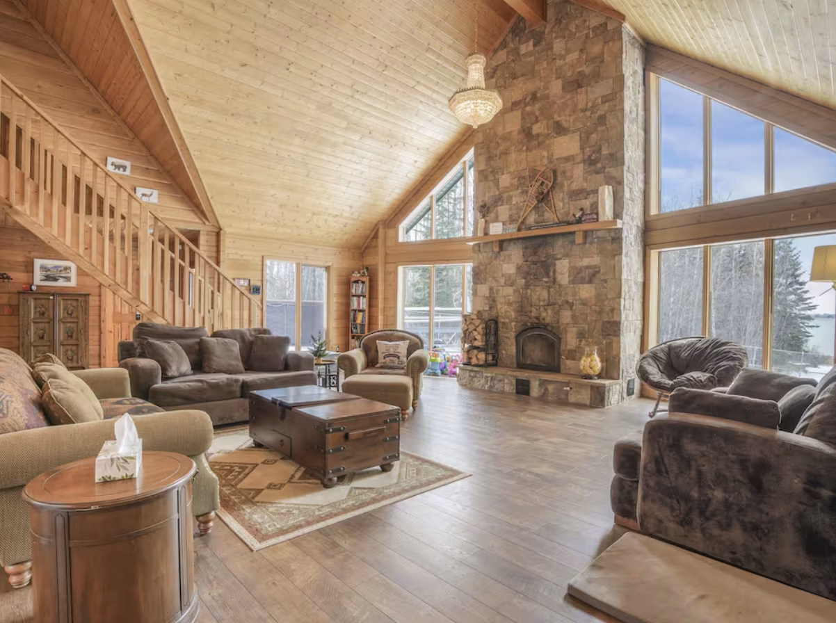 Great room with a stone fireplace in the Lessard Lake log home